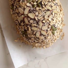 A seeded sourdough boule crusted with almonds and pumpkin seeds